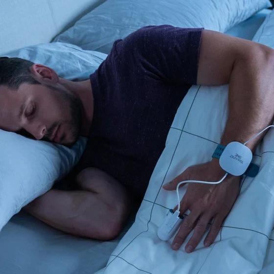Man sleeping while wearing a WatchPAT home sleep test device on his wrist